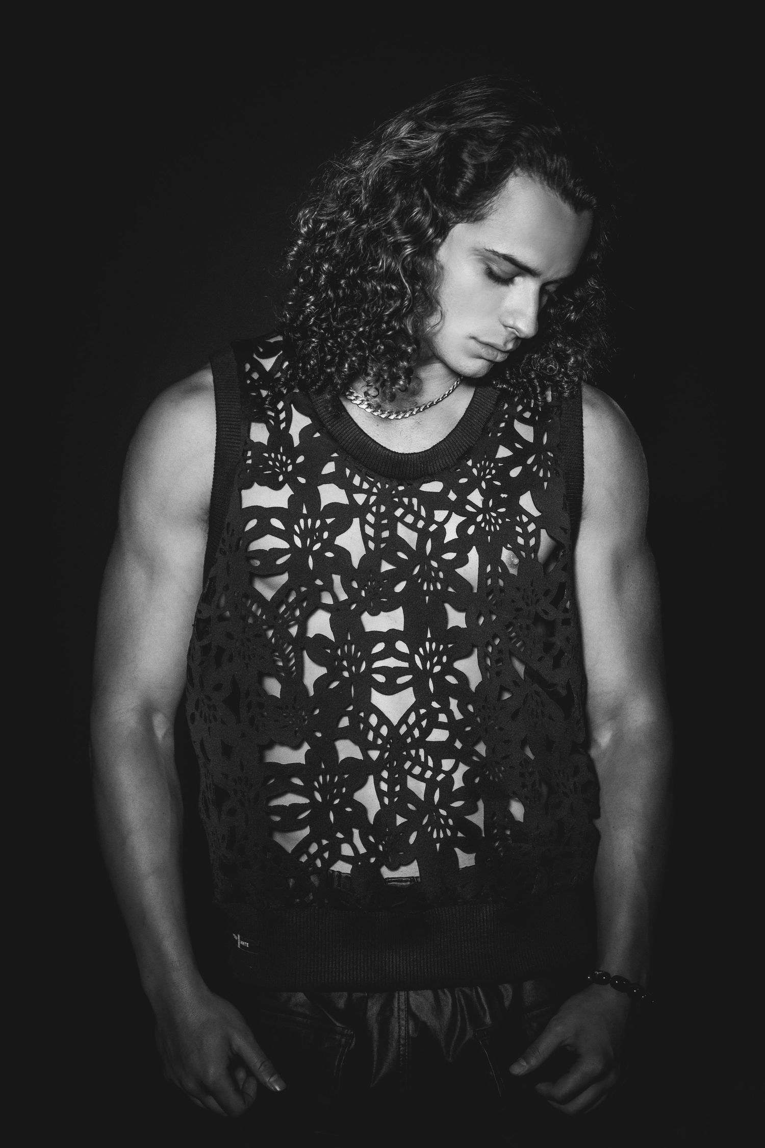 Dramatic black and white portrait series showing intricate lace pattern details on dark clothing against dark background.