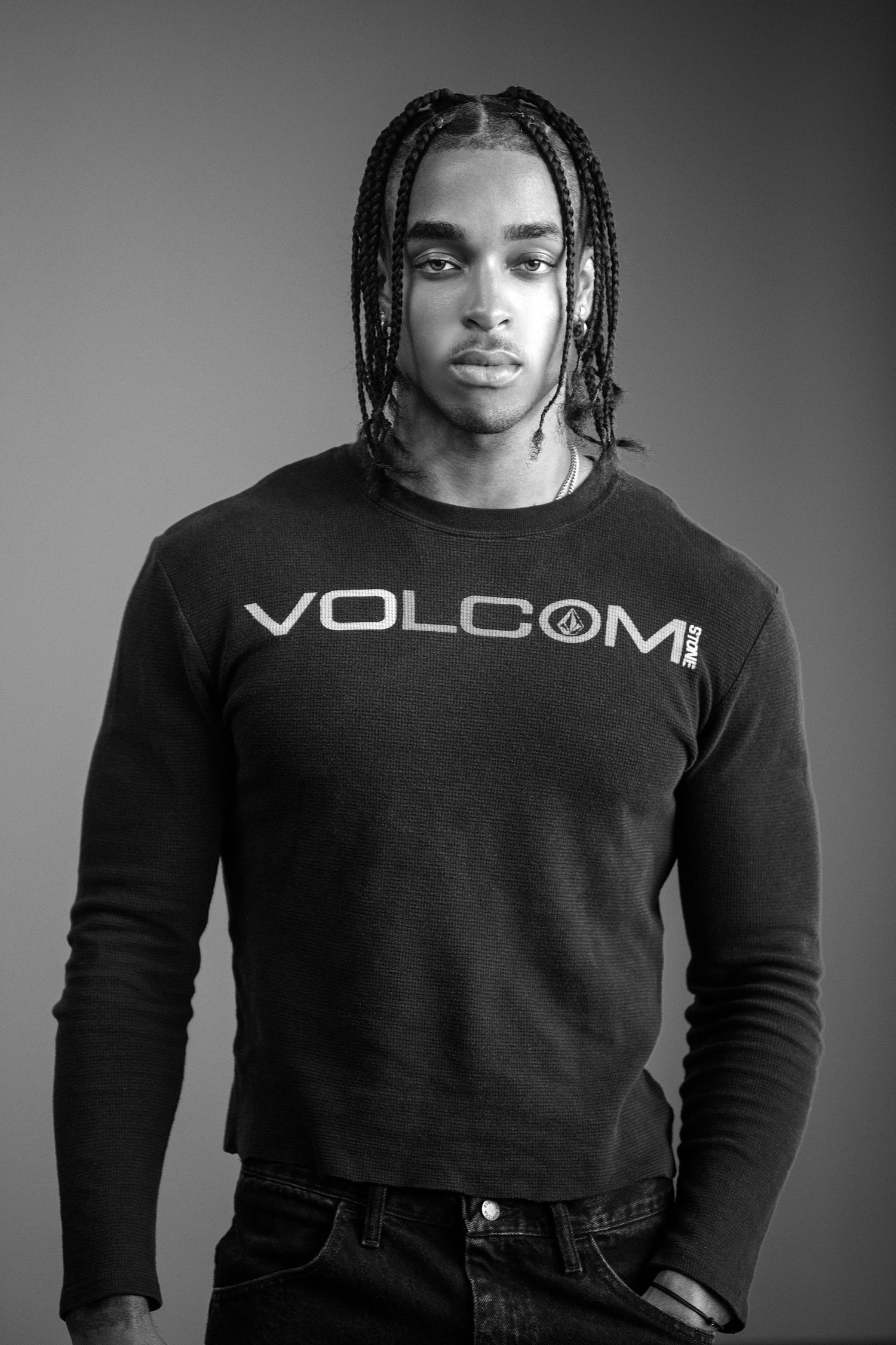 Black and white portrait of someone wearing a Volcom branded long sleeve shirt and braided hairstyle.