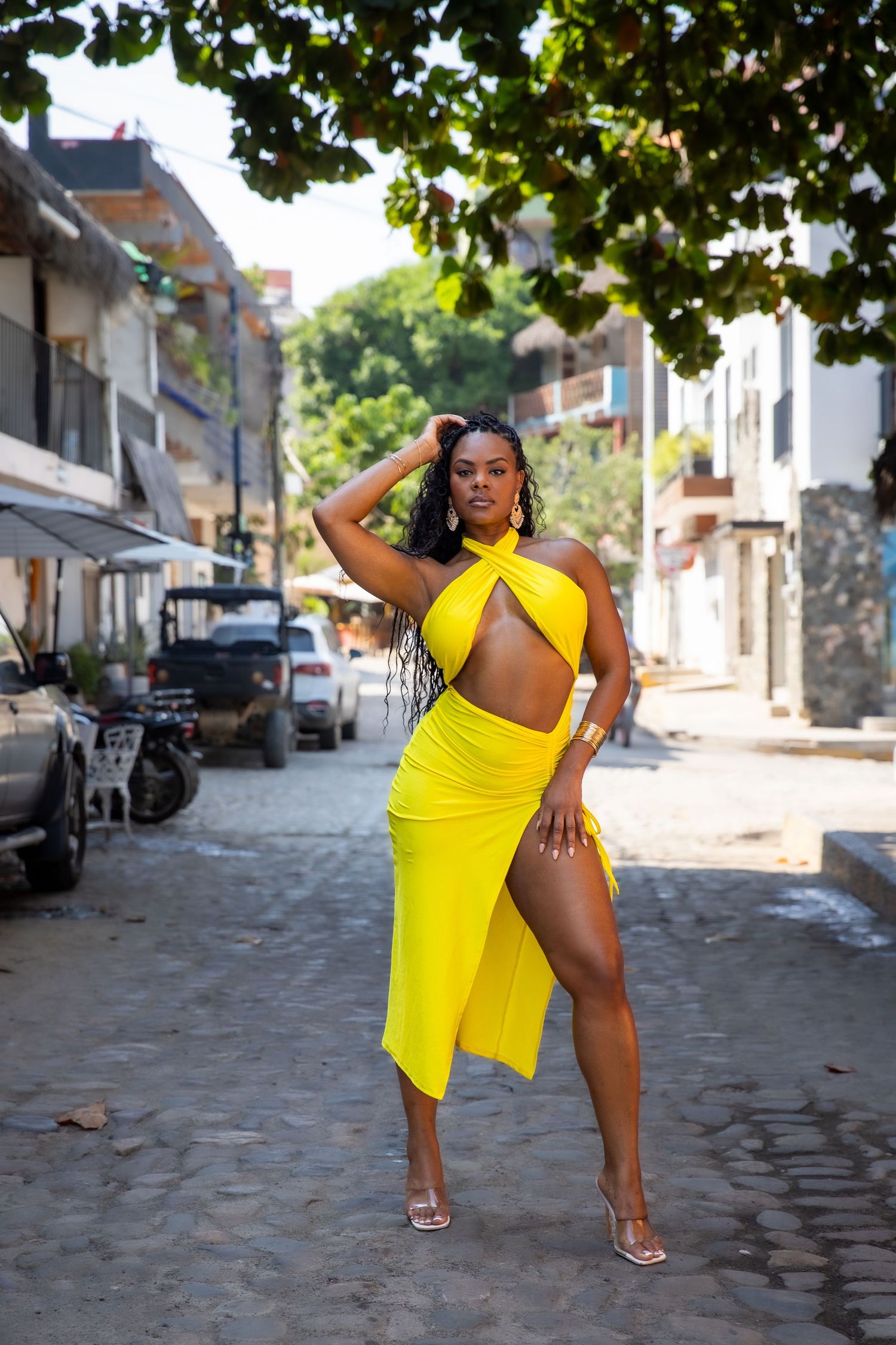 Woman in yellow dress strikes dynamic dance poses on a cobblestone street in a series of four photos.