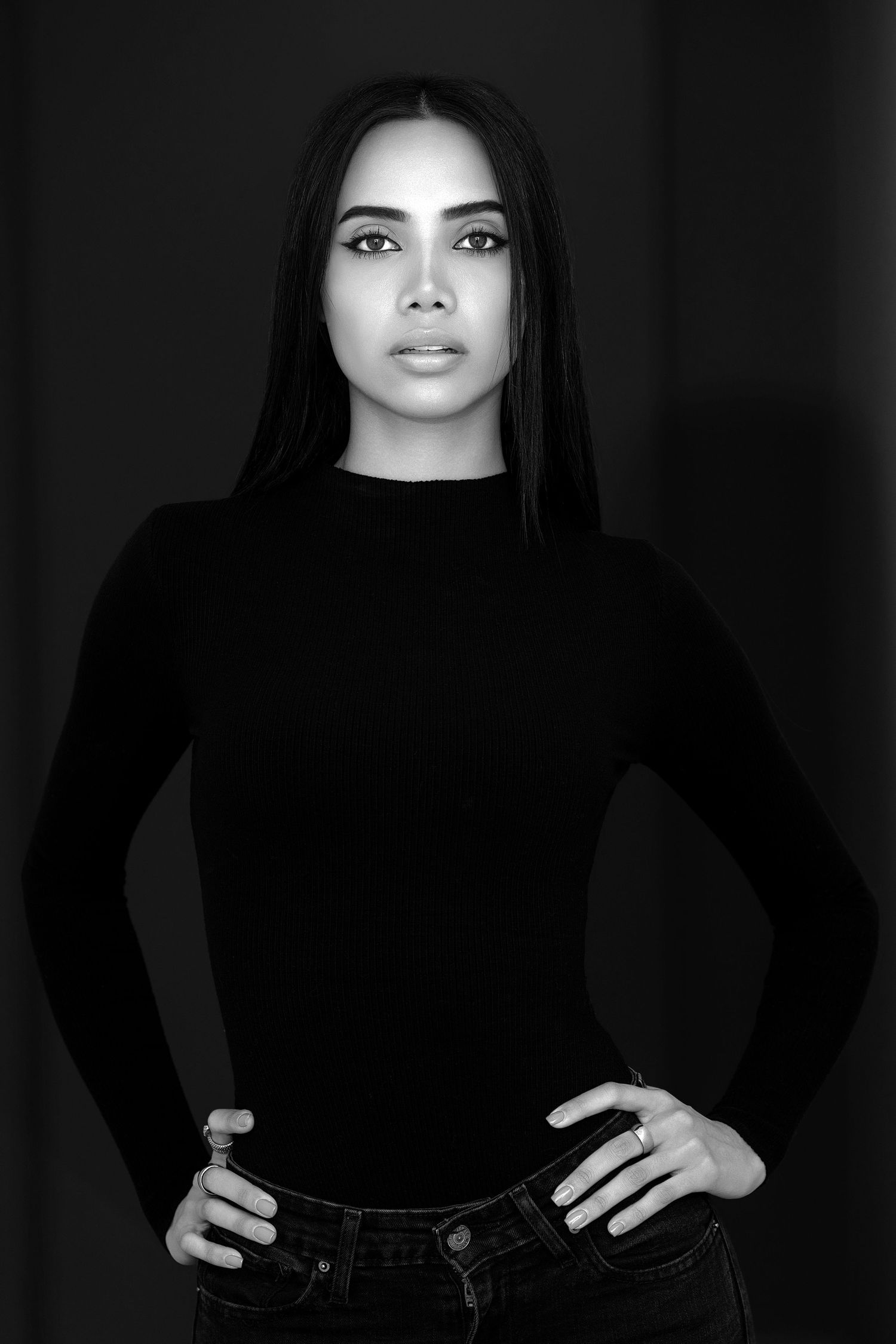A black and white photo series showing a person in dark clothing against a dark background posing in different positions.
