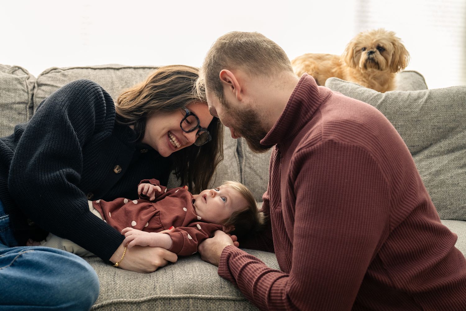 Couple relaxing on couch at home with their small dog in casual setting.