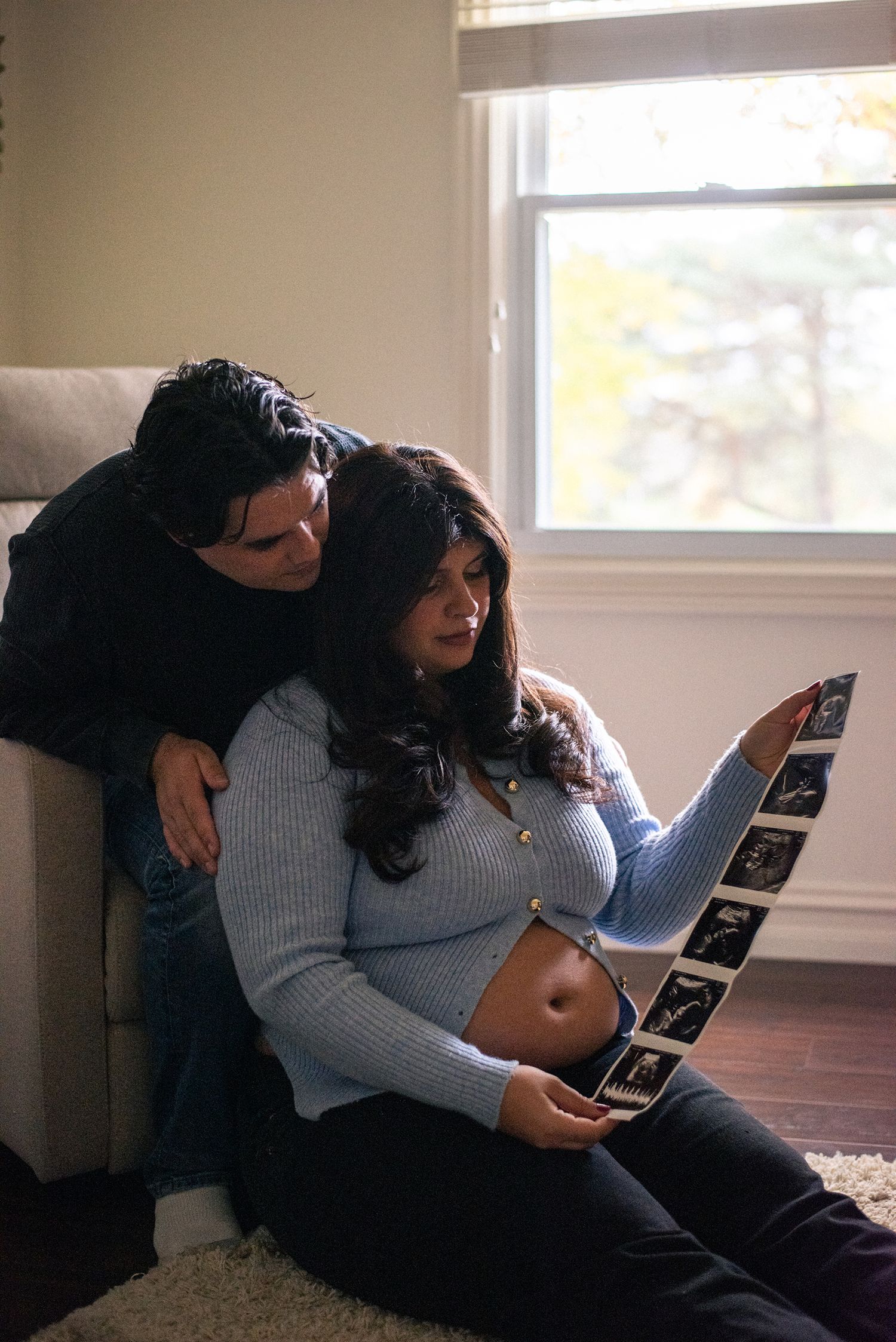 Couple sharing intimate moment while looking at ultrasound photos together.