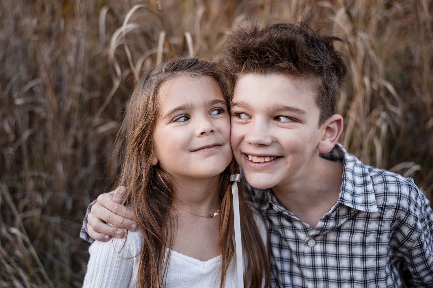 Couple embracing in a rustic outdoor setting with autumn foliage and natural light.