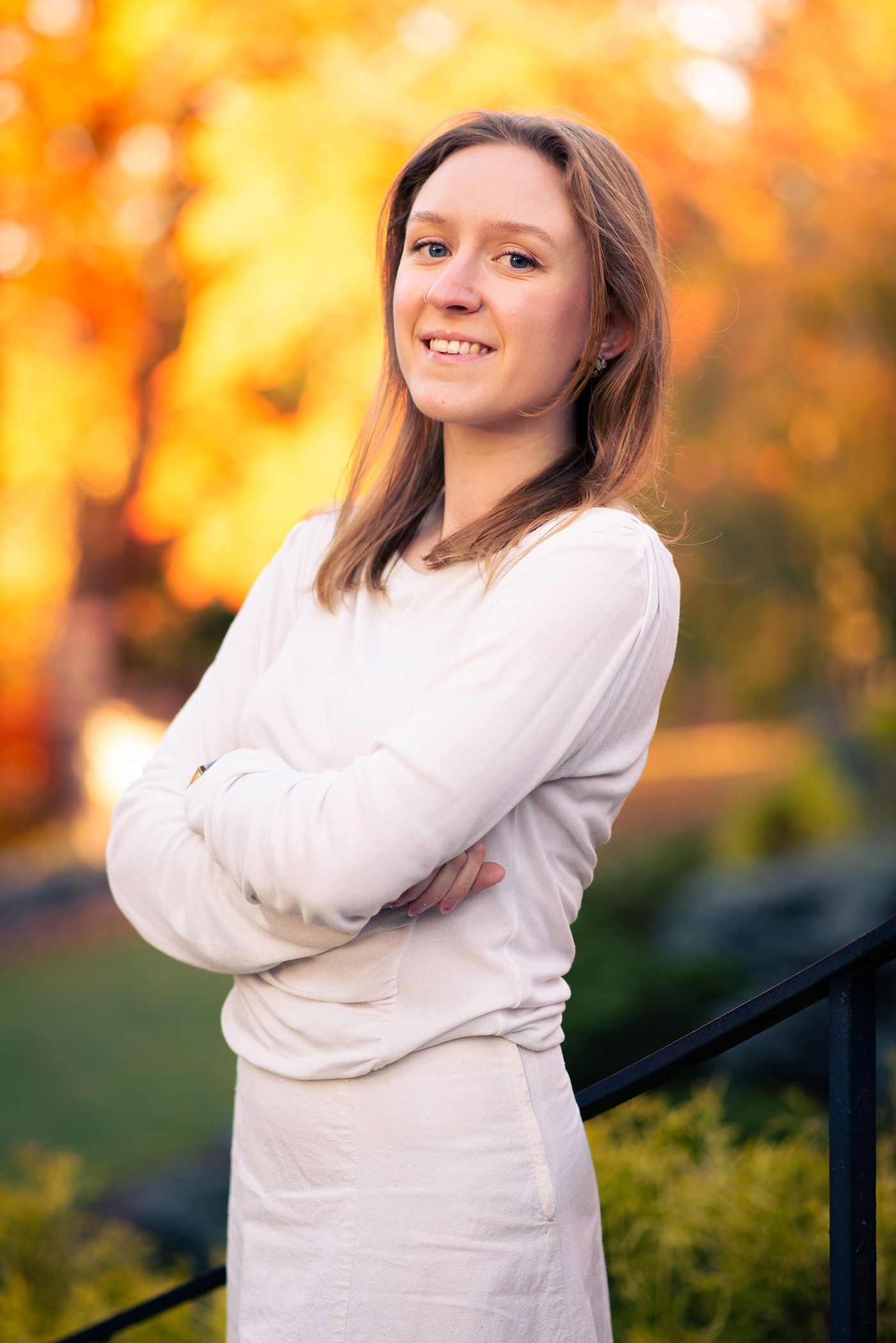 Portrait session in autumn setting with golden sunlight and natural backdrop.