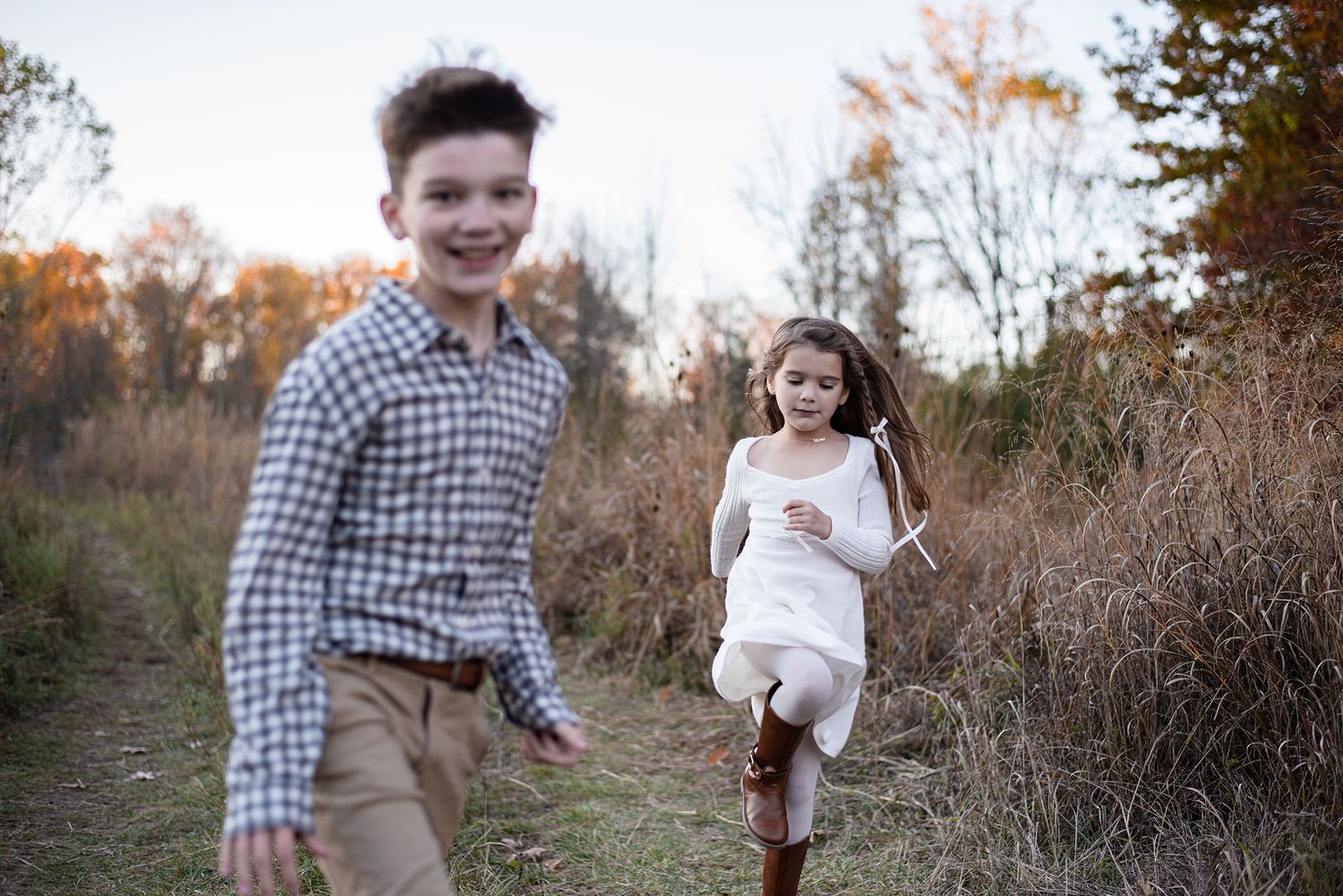 Family walking together on outdoor path surrounded by autumn foliage.