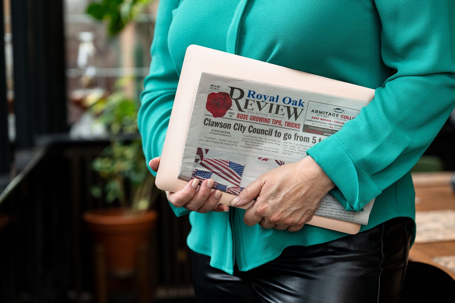 Close-up of hands holding educational materials with teal colored clothing visible.