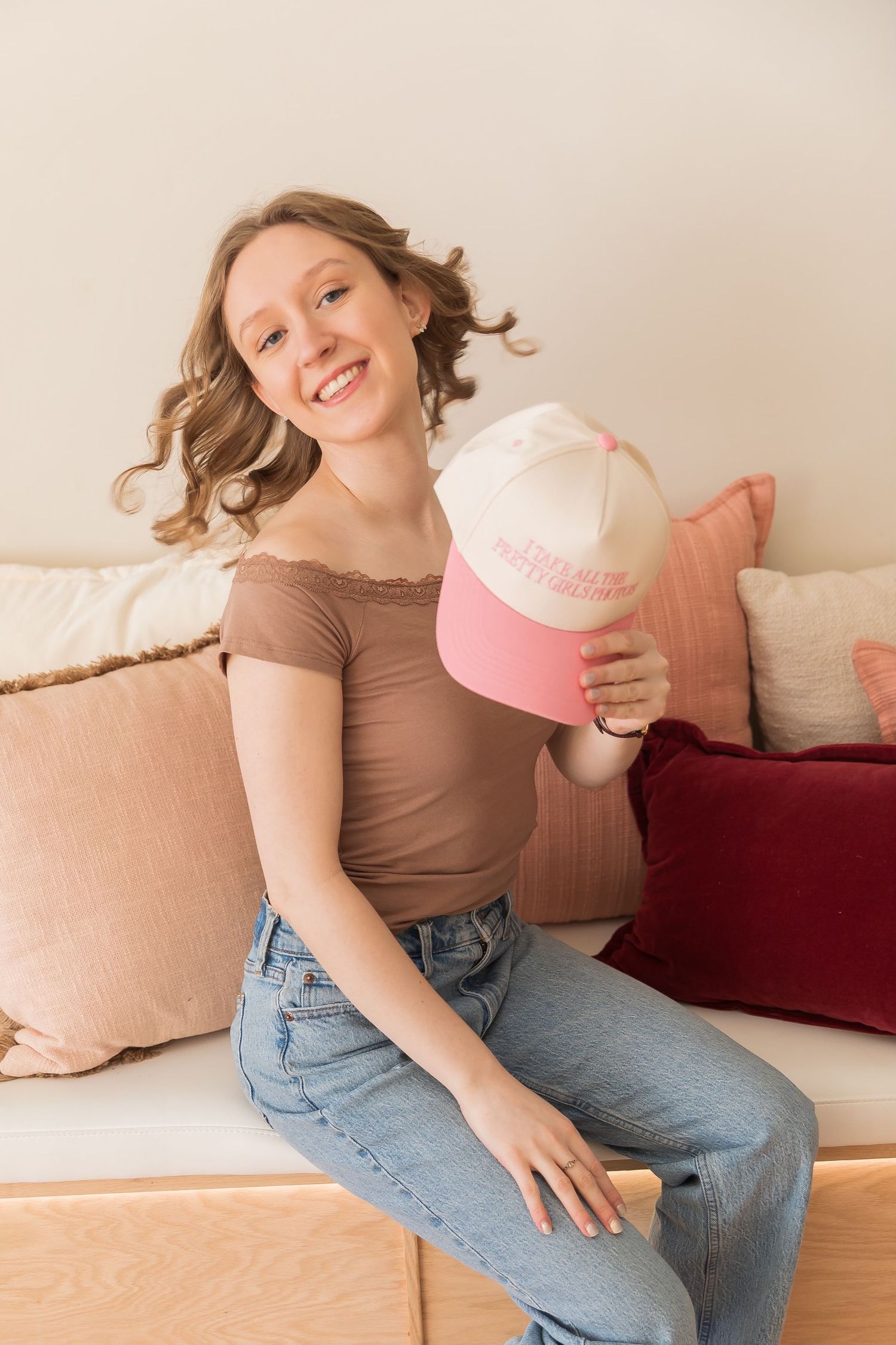 Person in brown shirt and jeans relaxing on beige couch with pink heart pillow.