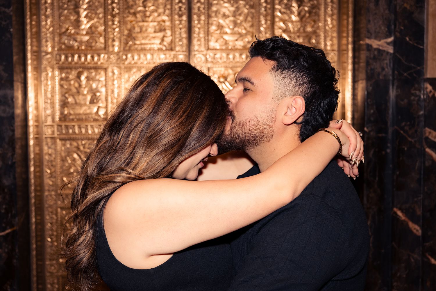 Romantic couple sharing intimate moments against a dark backdrop with dramatic lighting.