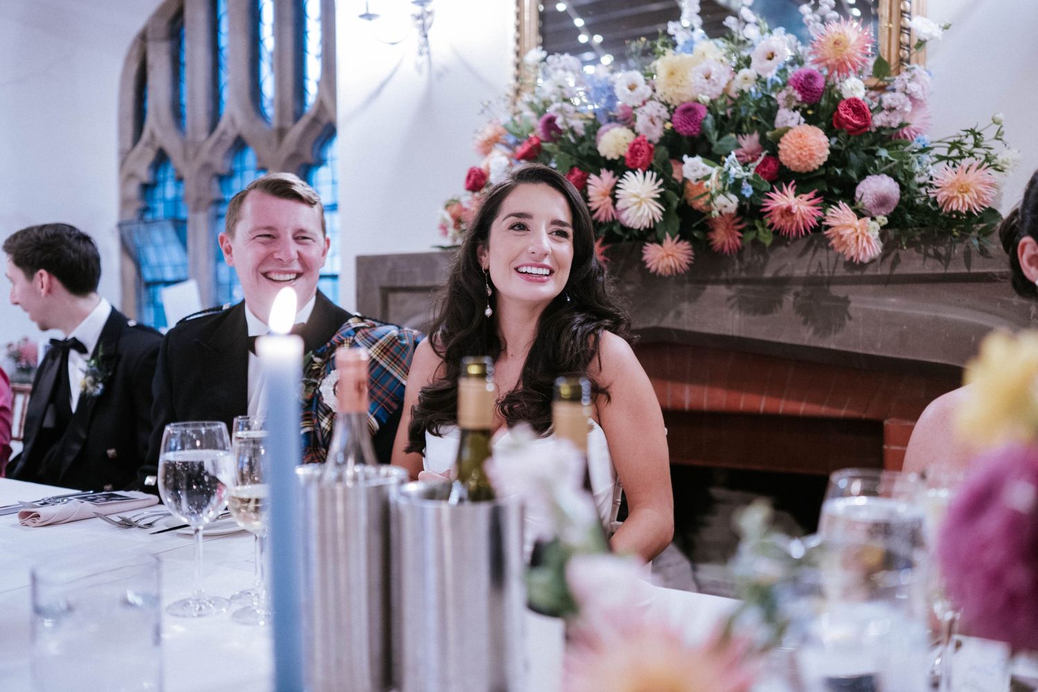 Elegant wedding reception table decorated with pink floral centerpieces and candlelight.