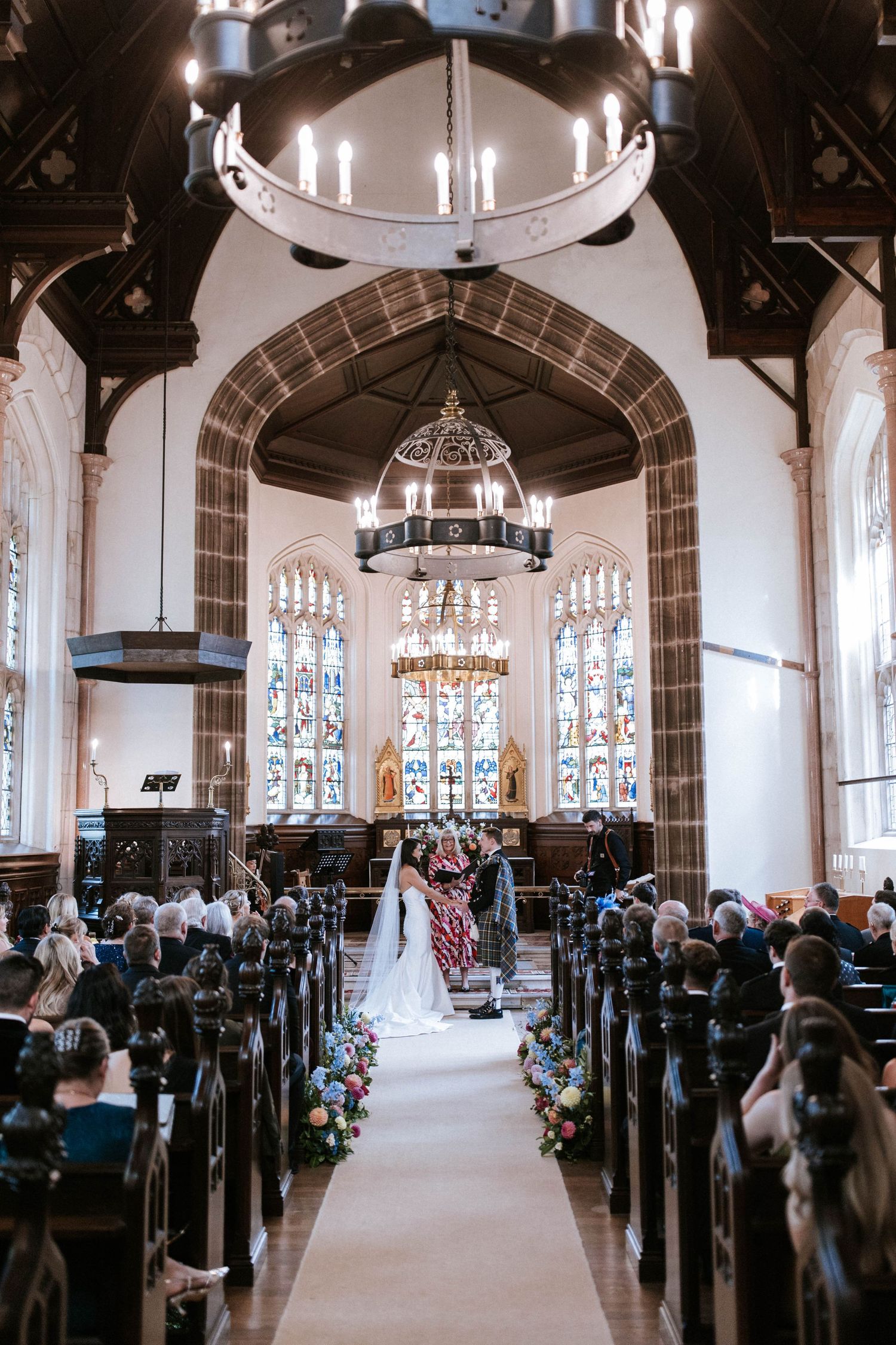 Gothic church interior with vaulted ceilings and stained glass windows during a wedding ceremony.