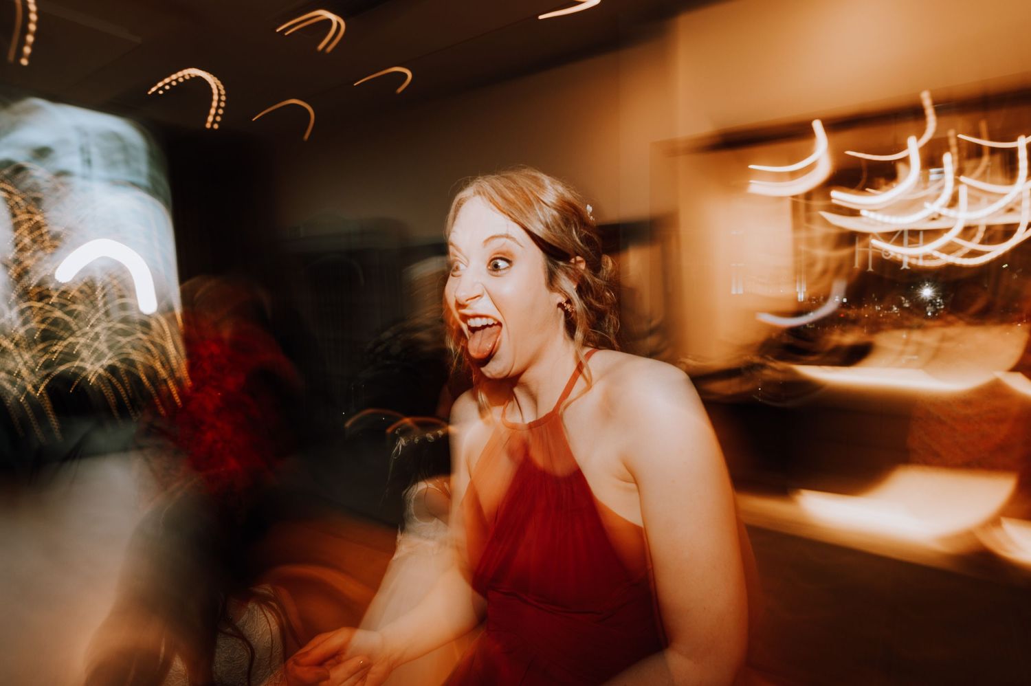 Wedding reception guests dancing and celebrating on a dimly lit dance floor with warm lighting. Meldrum House Wedding Photography.