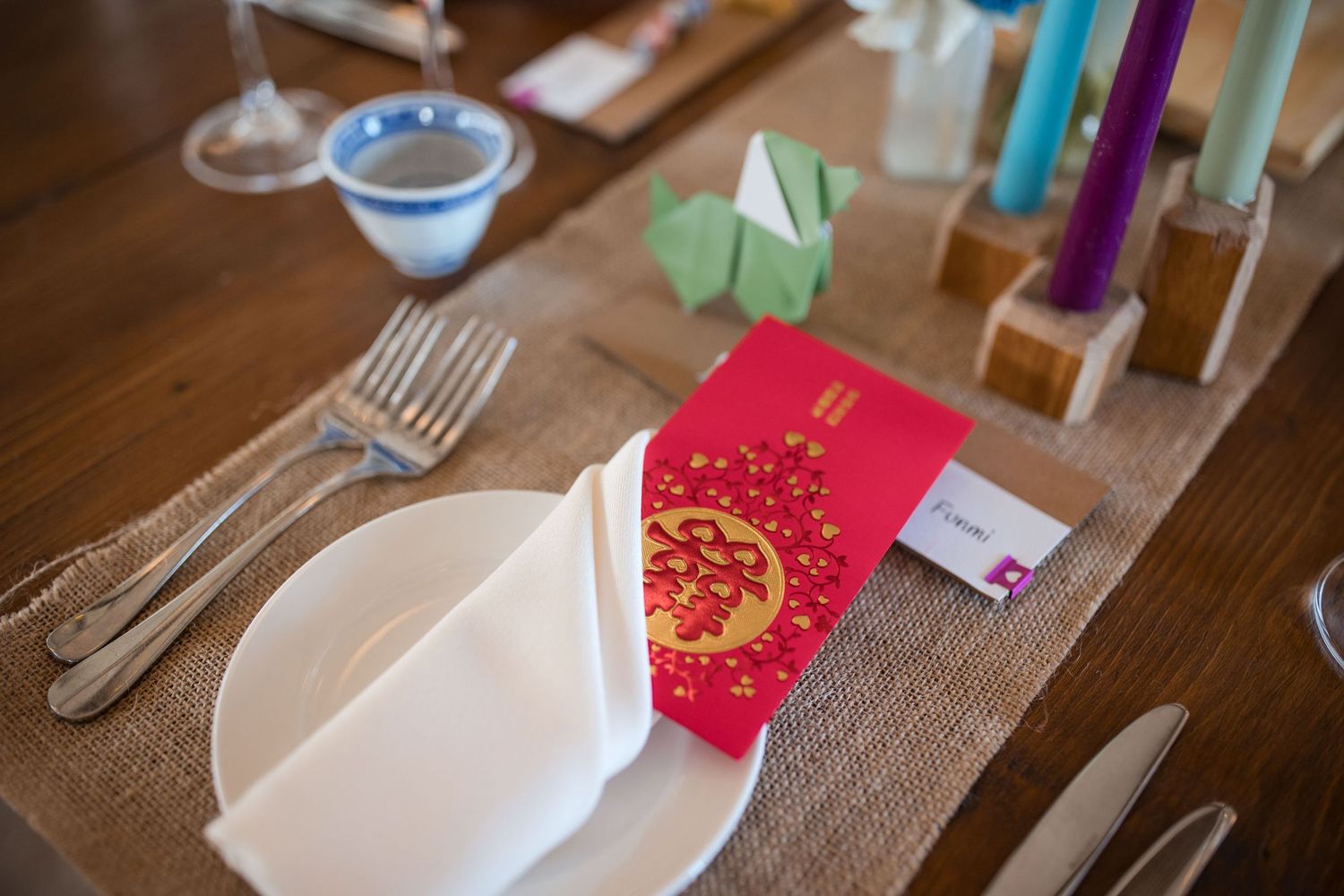 Wedding reception place settings with candles and elegant tableware on a rustic wooden surface.