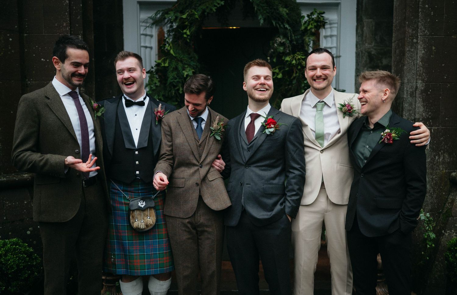 Drumtochty Castle  Wedding Photography. A group of friends in formal attire including kilts pose together at an event.