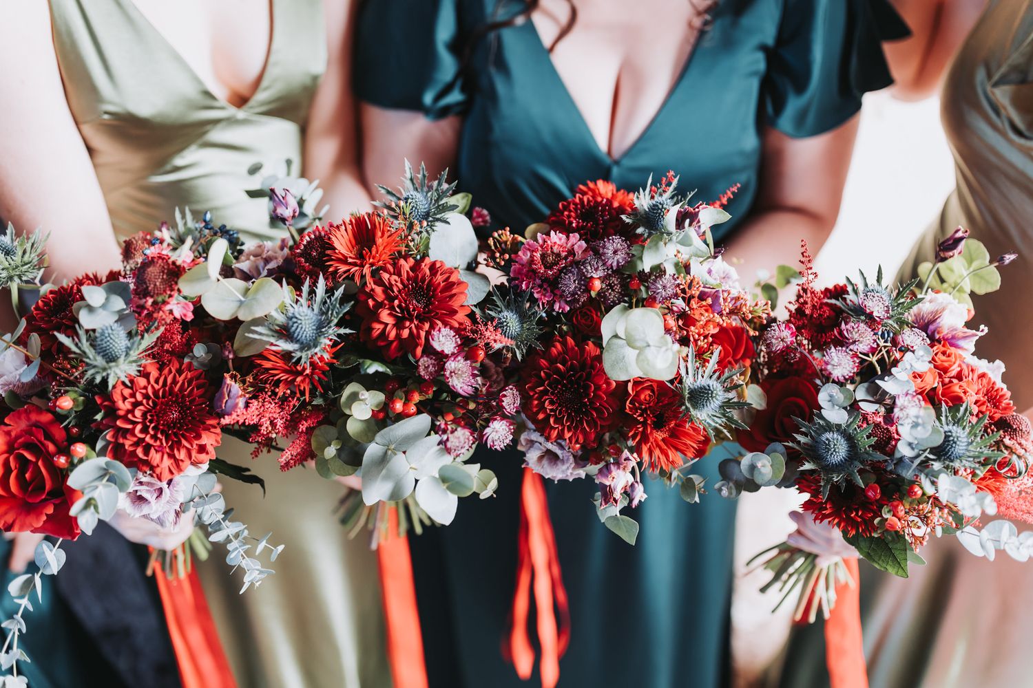 Wedding bouquets in deep red and white flowers with greenery arranged in a row against a dark background.