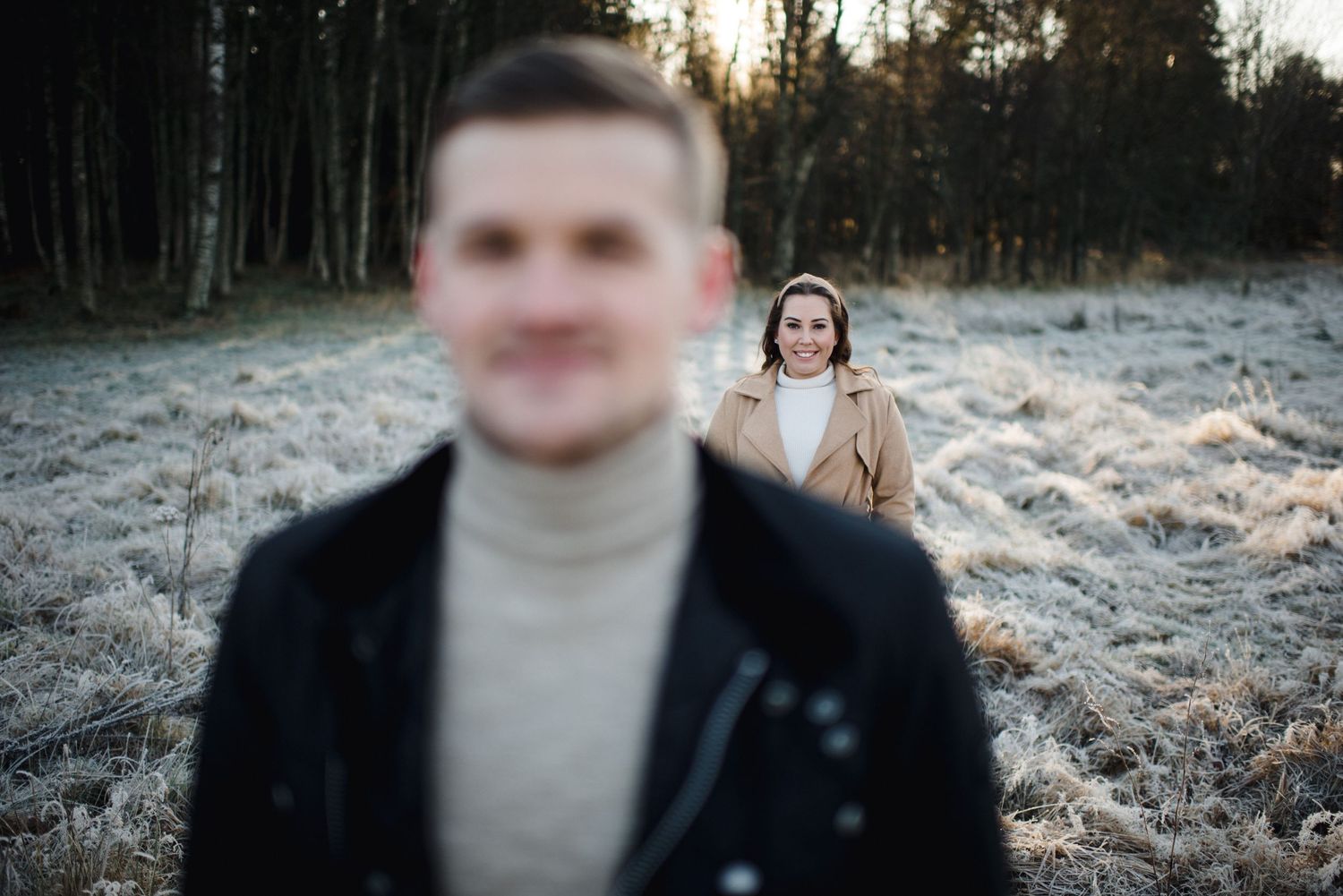 An artistic engagement photo with focus play between the couple in a winter setting.
