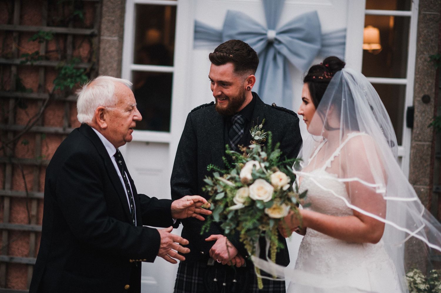 Elderly guest congratulates newlyweds during outdoor wedding reception.