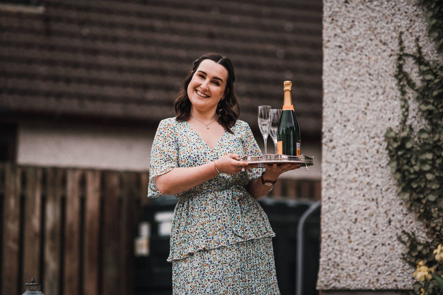 Server carries champagne tray at outdoor wedding reception.
