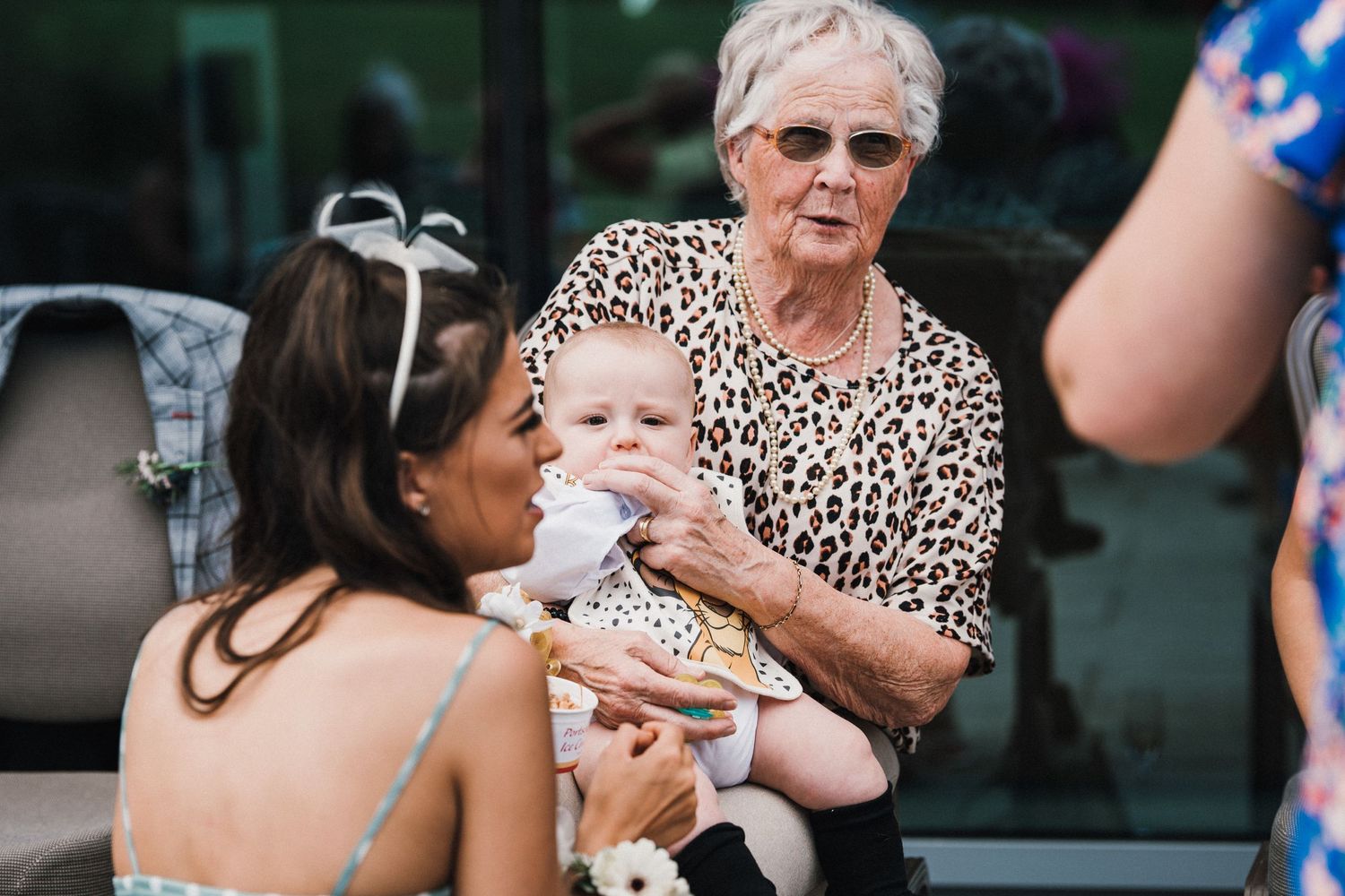 Three people interacting with a small baby at an outdoor event.