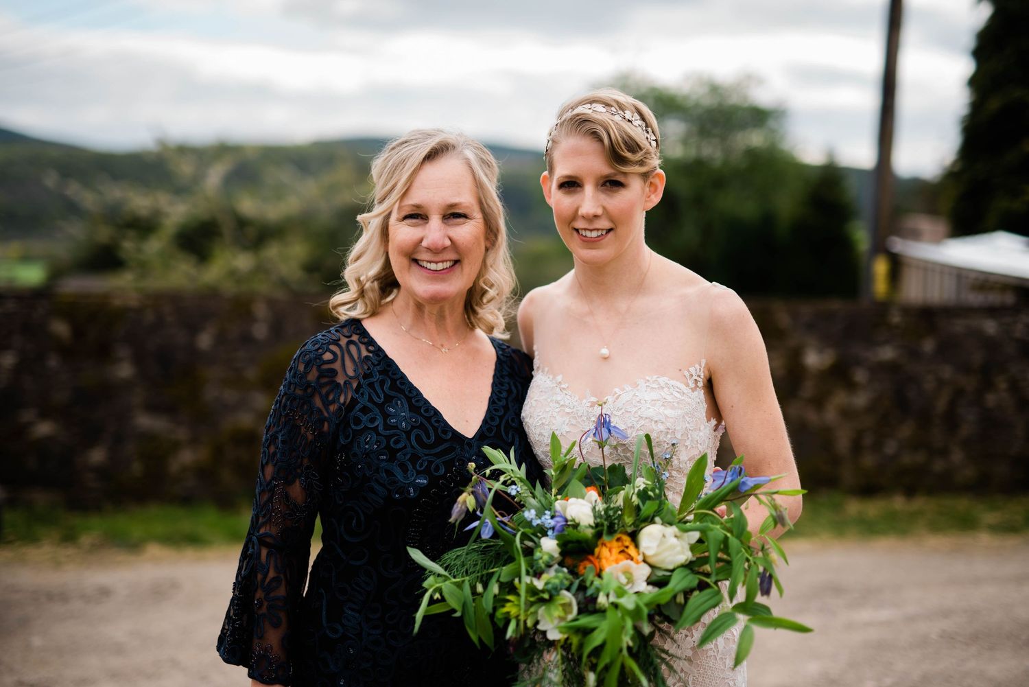 Elegant outdoor portrait with beautiful floral bouquet against countryside view.