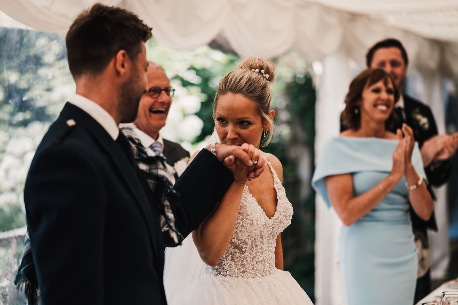 Emotional moment captured during wedding speeches under a white tent.