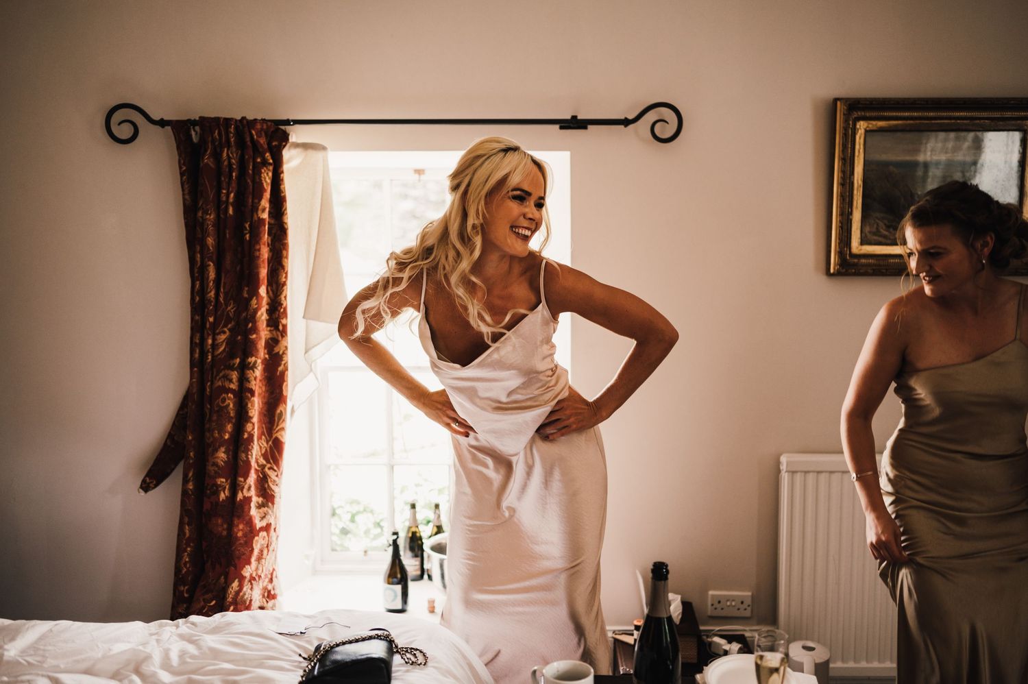 Getting ready scene with natural window light streaming into a bedroom on wedding morning.