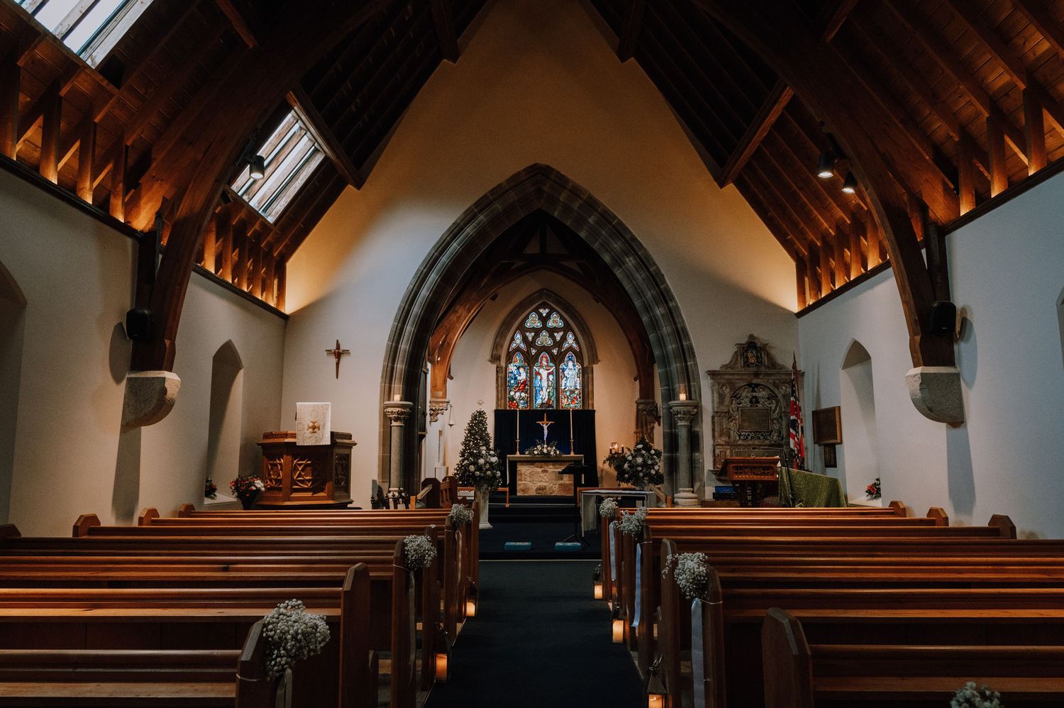 Interior of historic church with wooden beams and arched windows in dark atmospheric lighting.