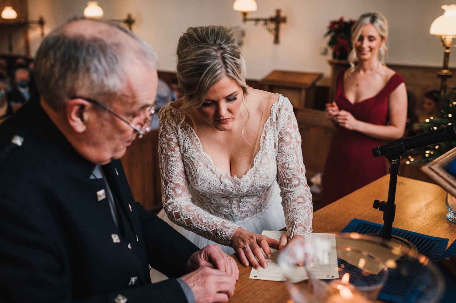 Signing ceremony at church altar with vintage lamp and Christmas decorations in background.