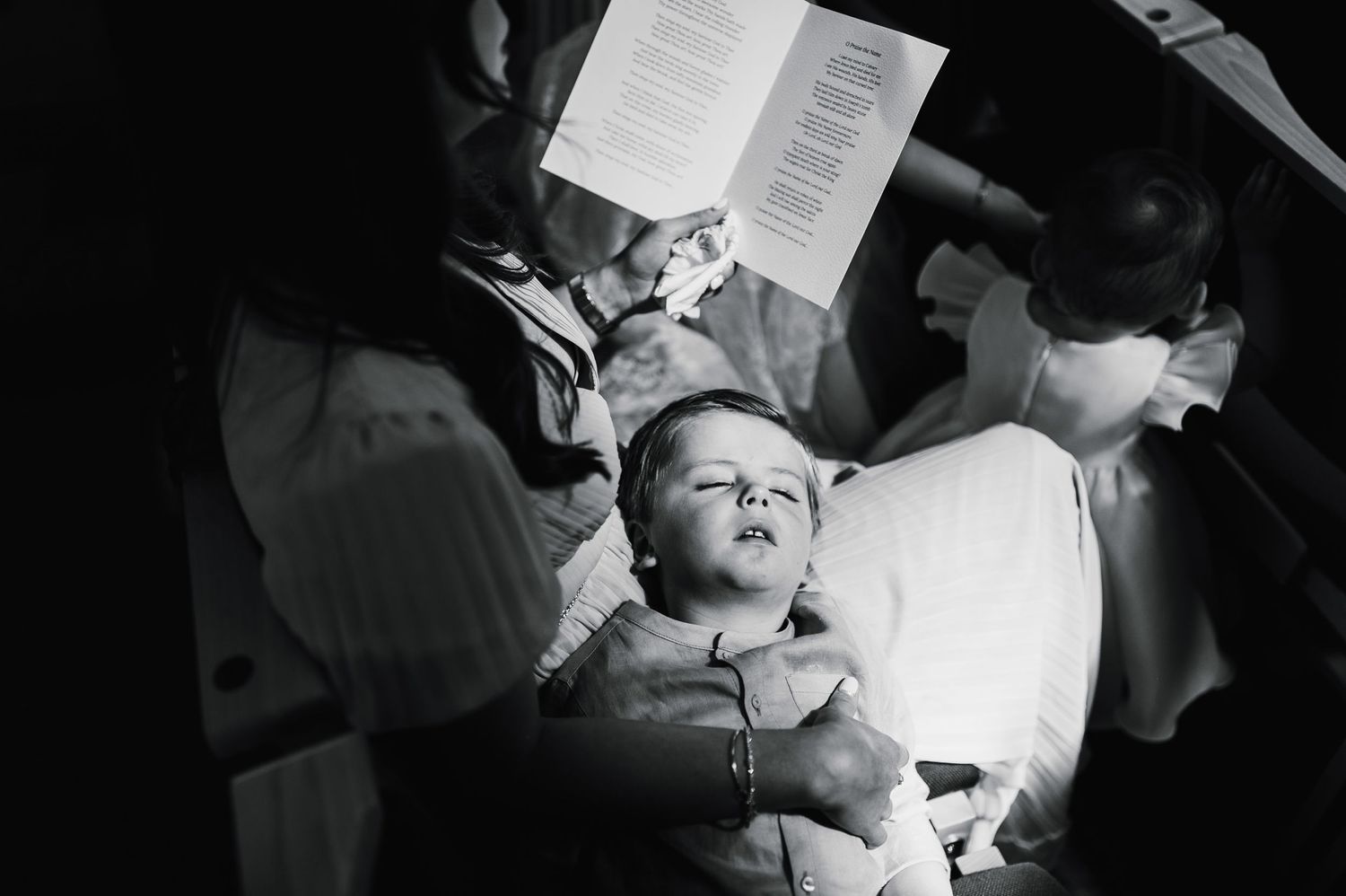 A black and white image of people reading from papers during a church gathering.
