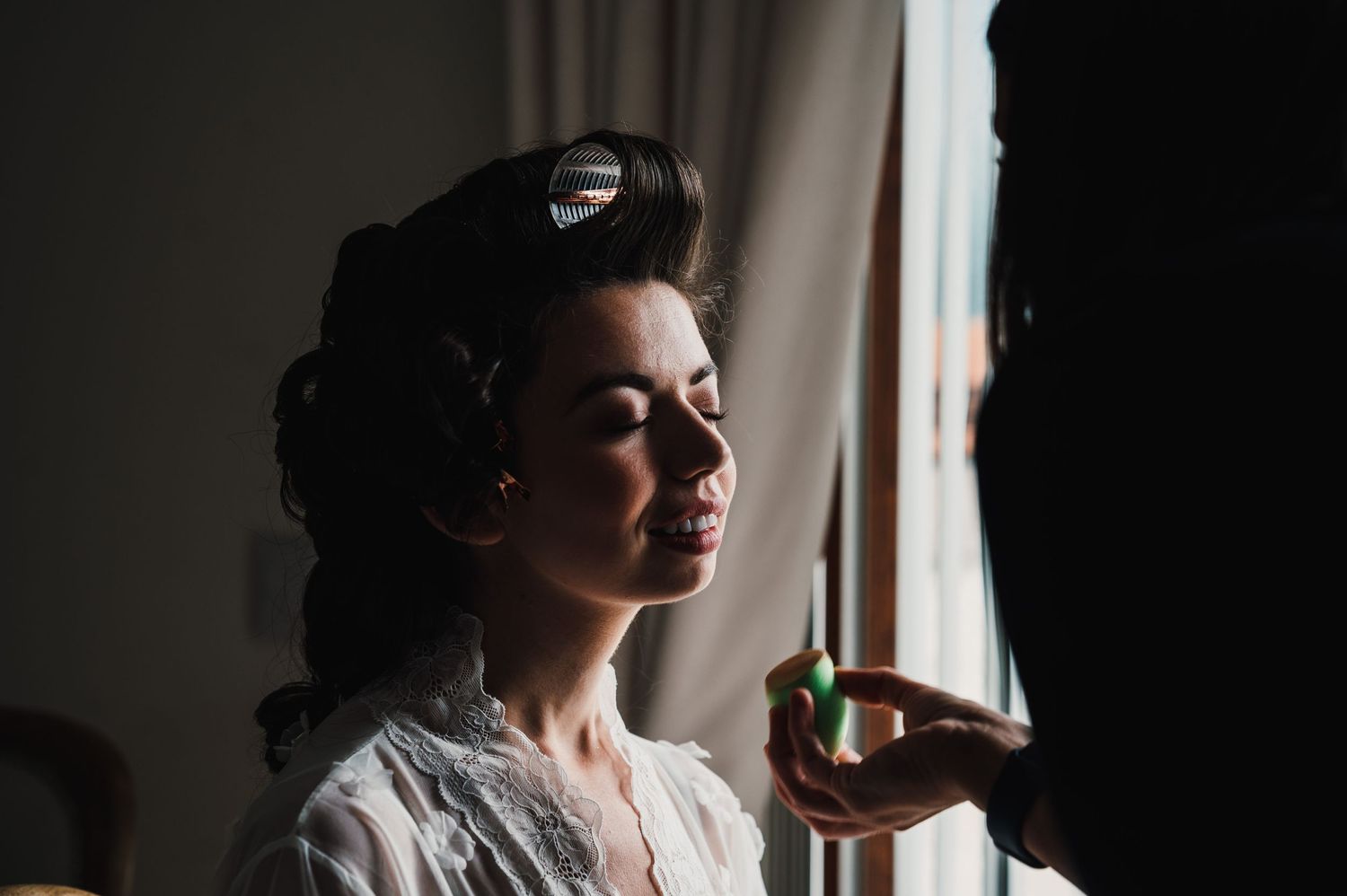 Silhouette of person with styled hair looking out window in dramatic lighting.