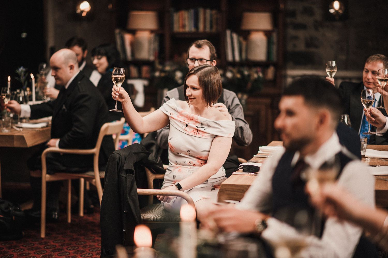Wedding reception guests raise their glasses in celebration at an elegant indoor venue.