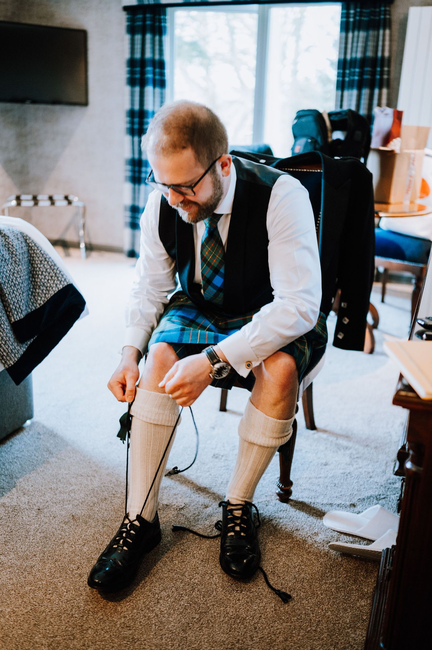 Traditional Scottish highland dress with kilt socks and formal attire being adjusted.