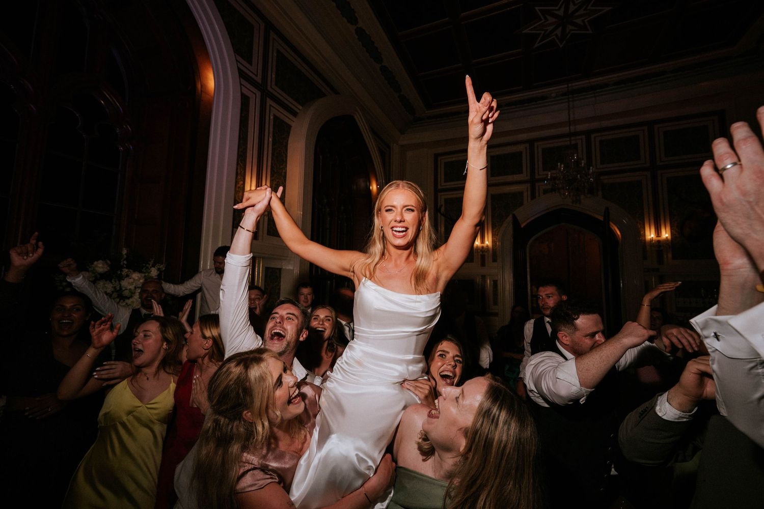 Dynamic wedding reception dancing captured in low light with celebratory atmosphere.