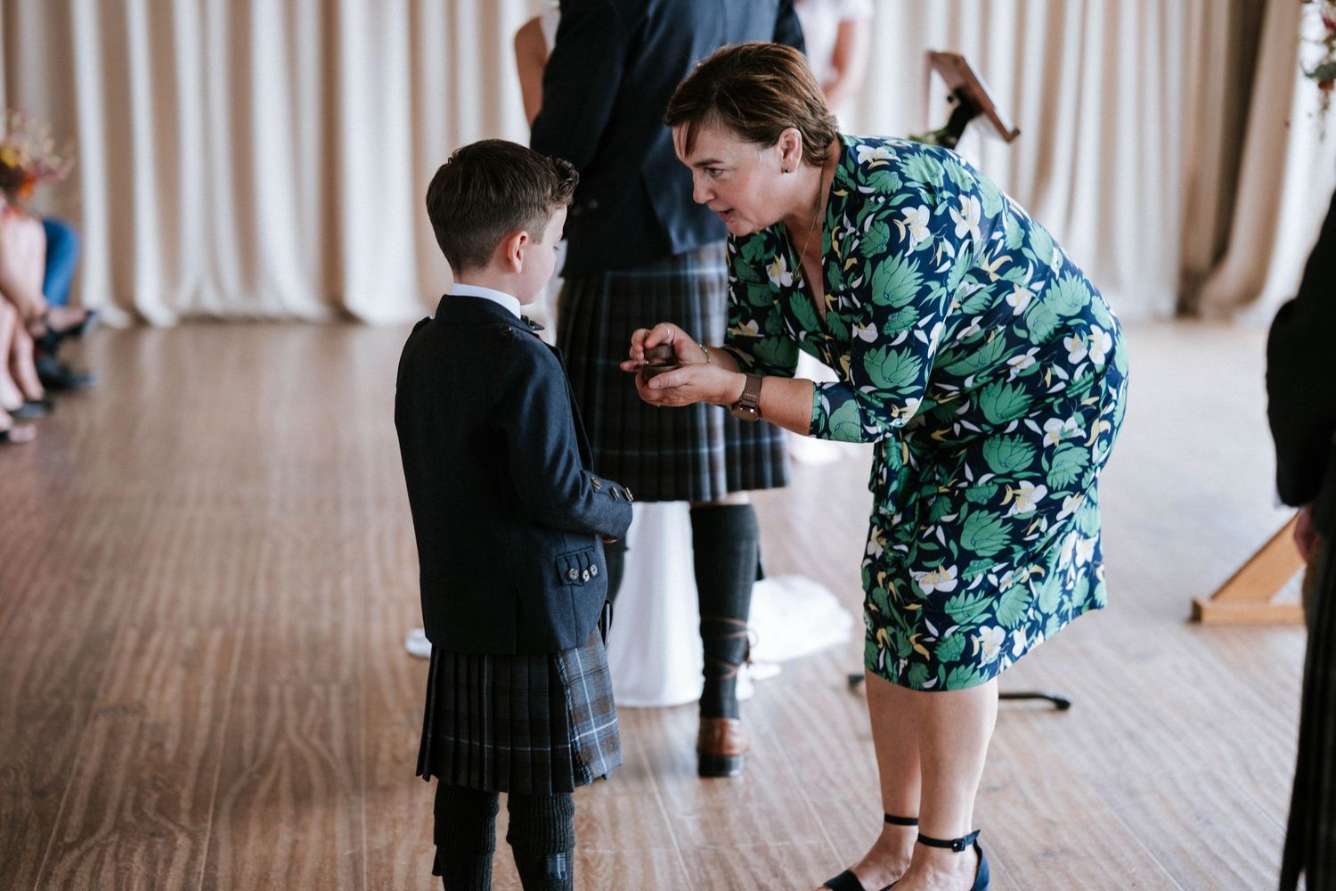 Wedding guests mingle and interact during an indoor reception with string lights overhead.