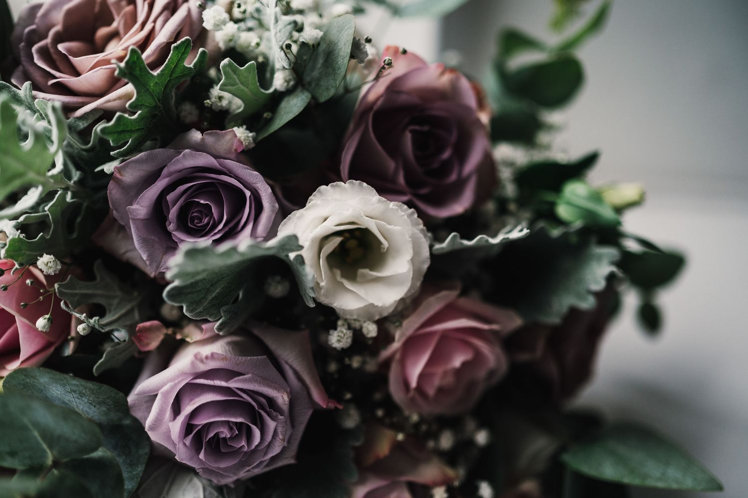 Elegant floral arrangement with purple and white roses mixed with lush greenery.