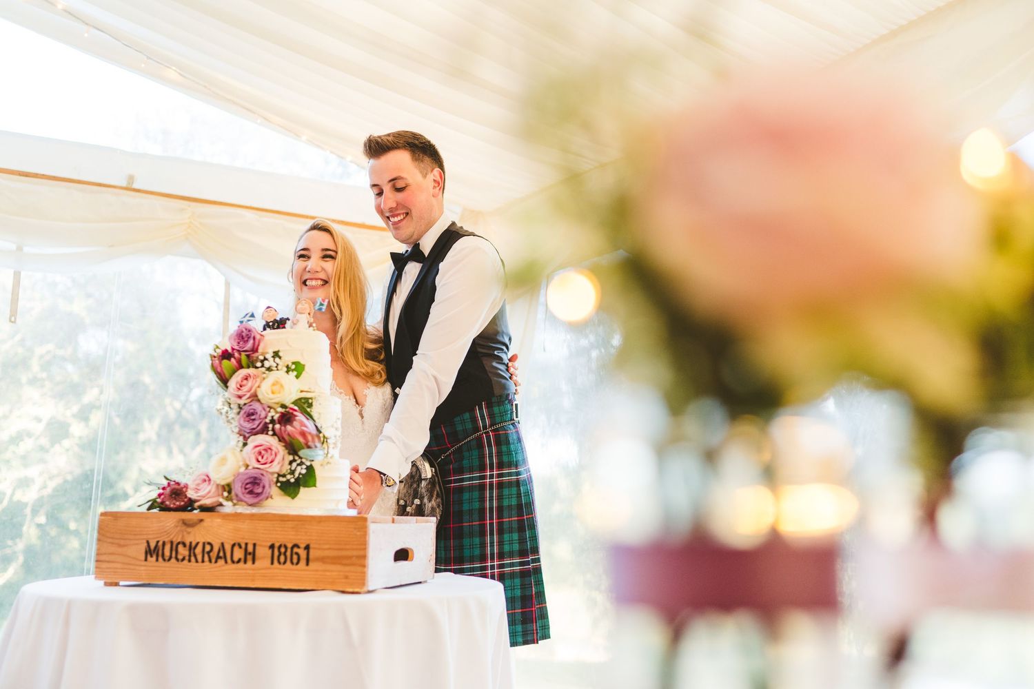 Wedding reception details with decorative lighting and floral arrangements on dining tables.