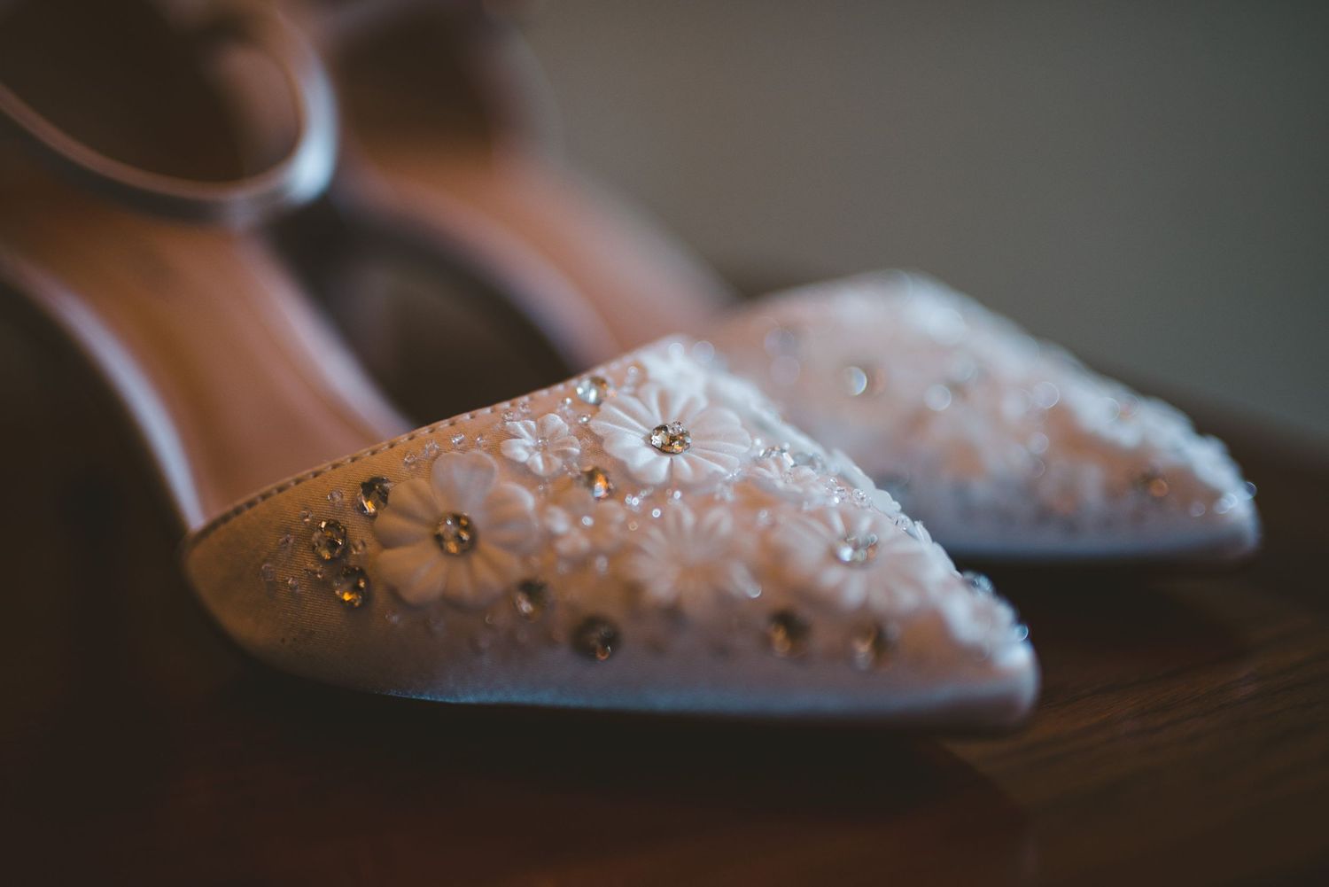 Close-up view of pink ballet pointe shoes with rhinestone embellishments in soft natural lighting.