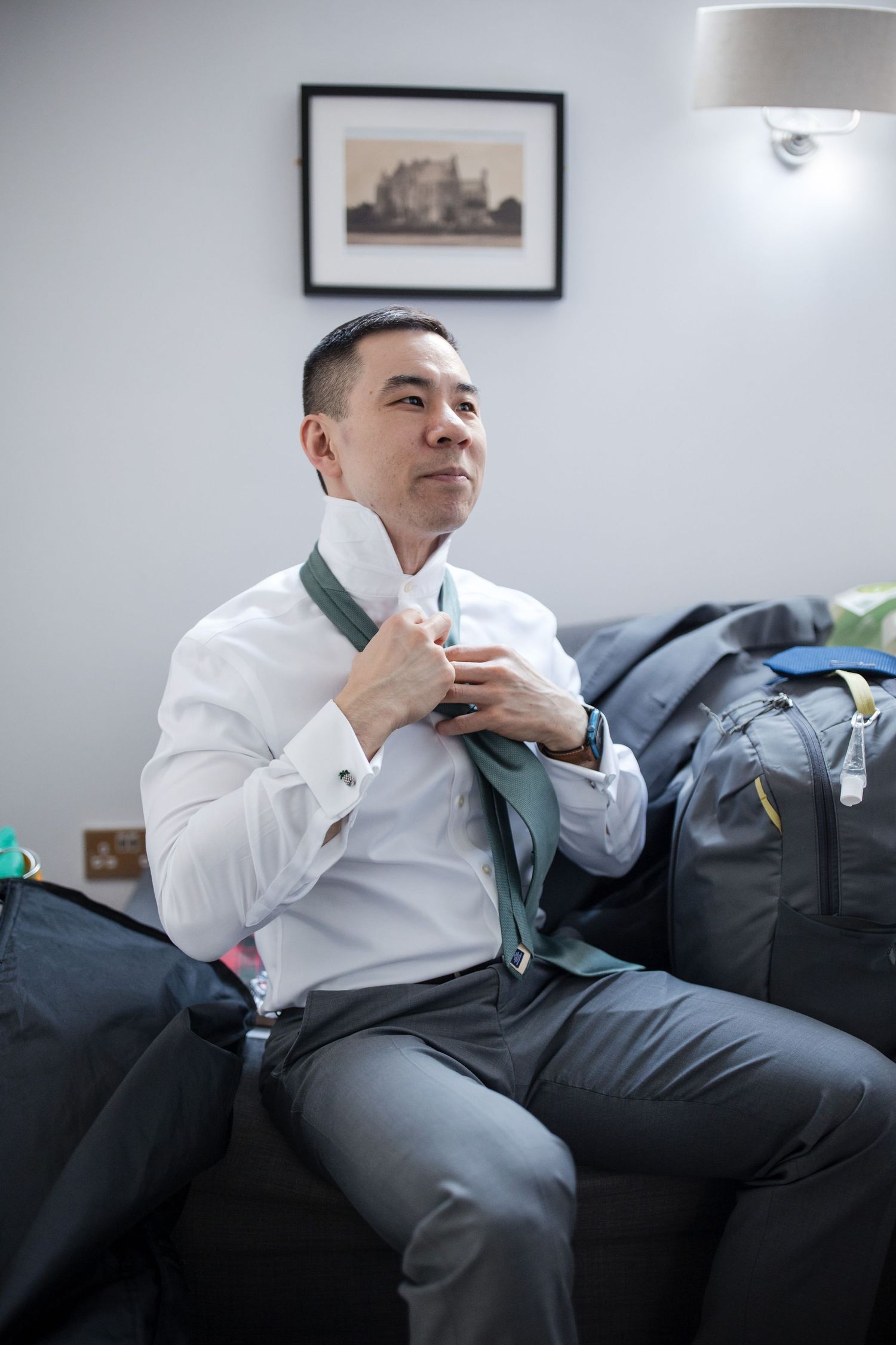 Person in white dress shirt relaxing on a black leather couch in a modern living room.