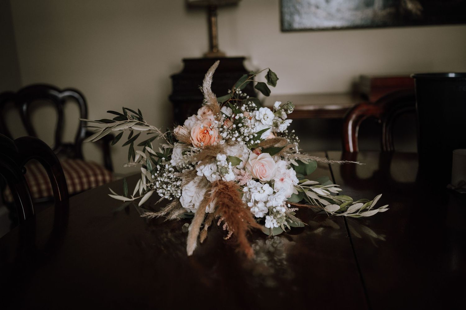 Romantic floral arrangement with peach and white flowers on dark wooden table.