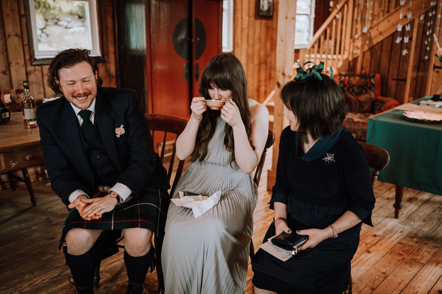 People sharing an emotional moment while seated in a rustic wooden interior.