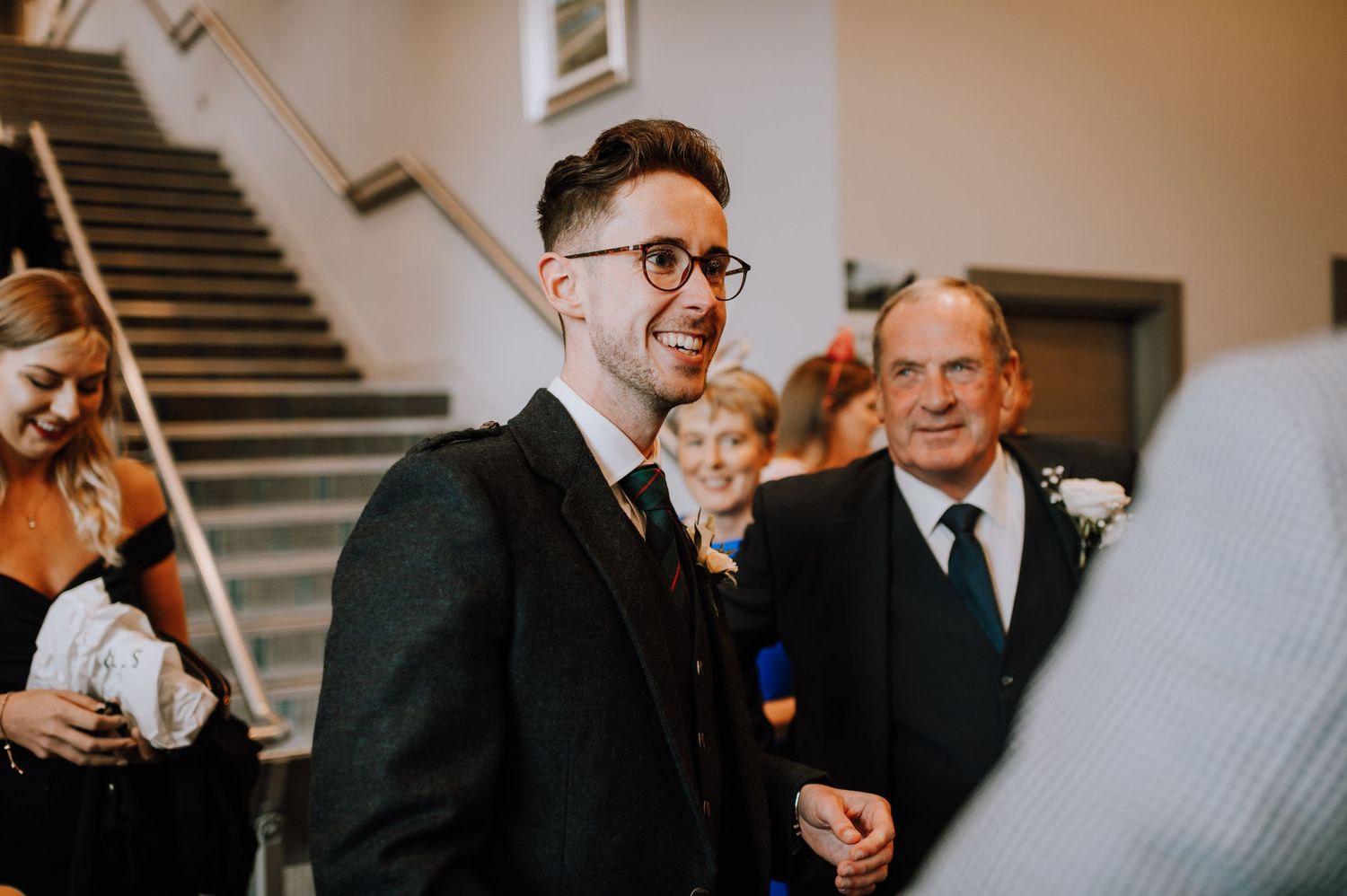 Elegant indoor wedding ceremony with guests gathered near a grand staircase.
