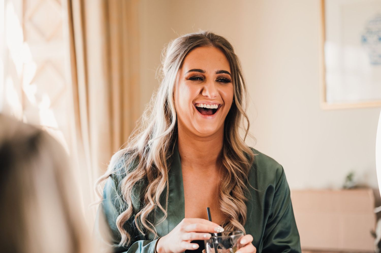 Candid moment of laughter during wedding morning preparations.