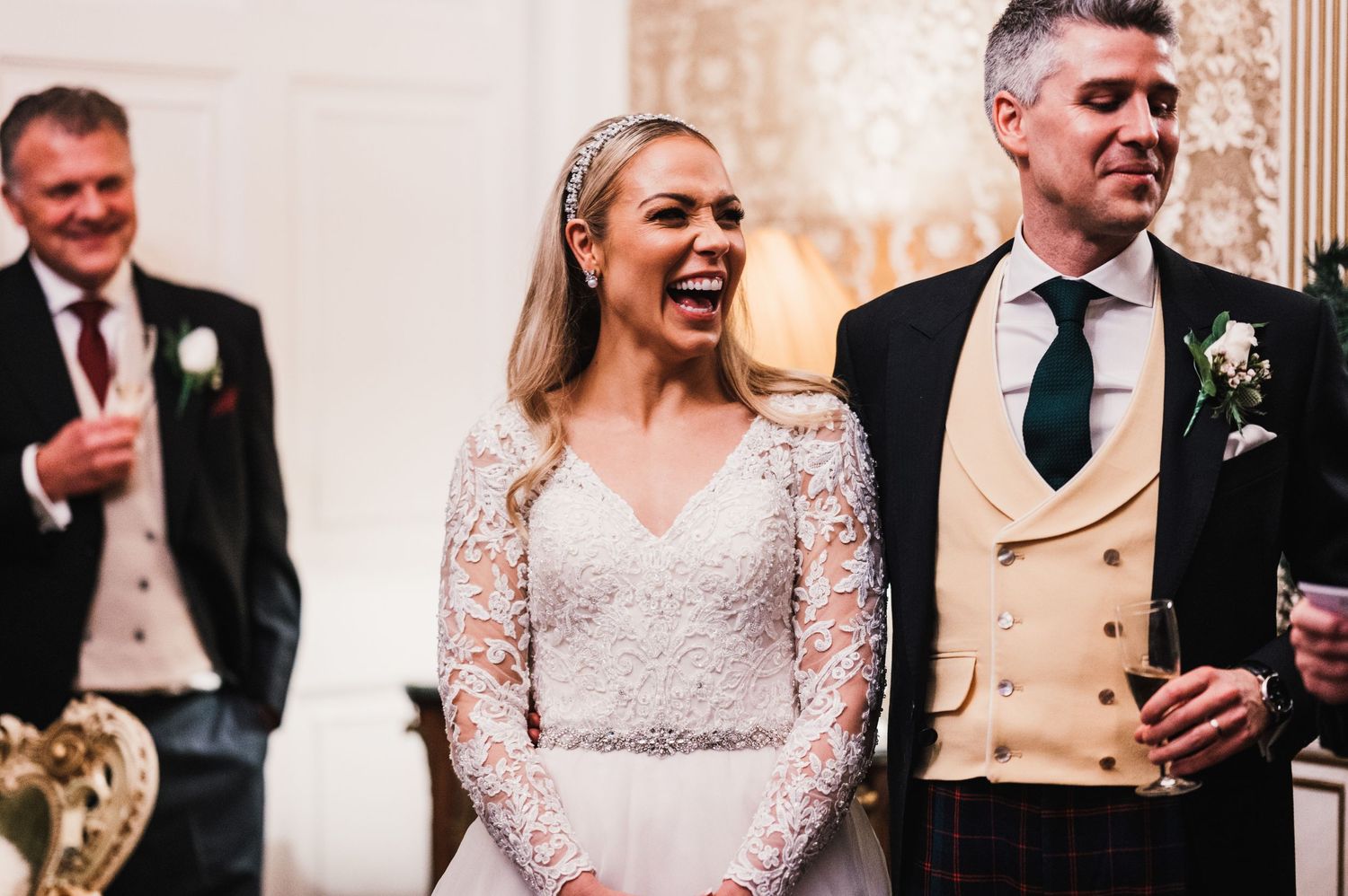 A joyful moment captured during wedding speeches in an elegant venue with ornate decor.