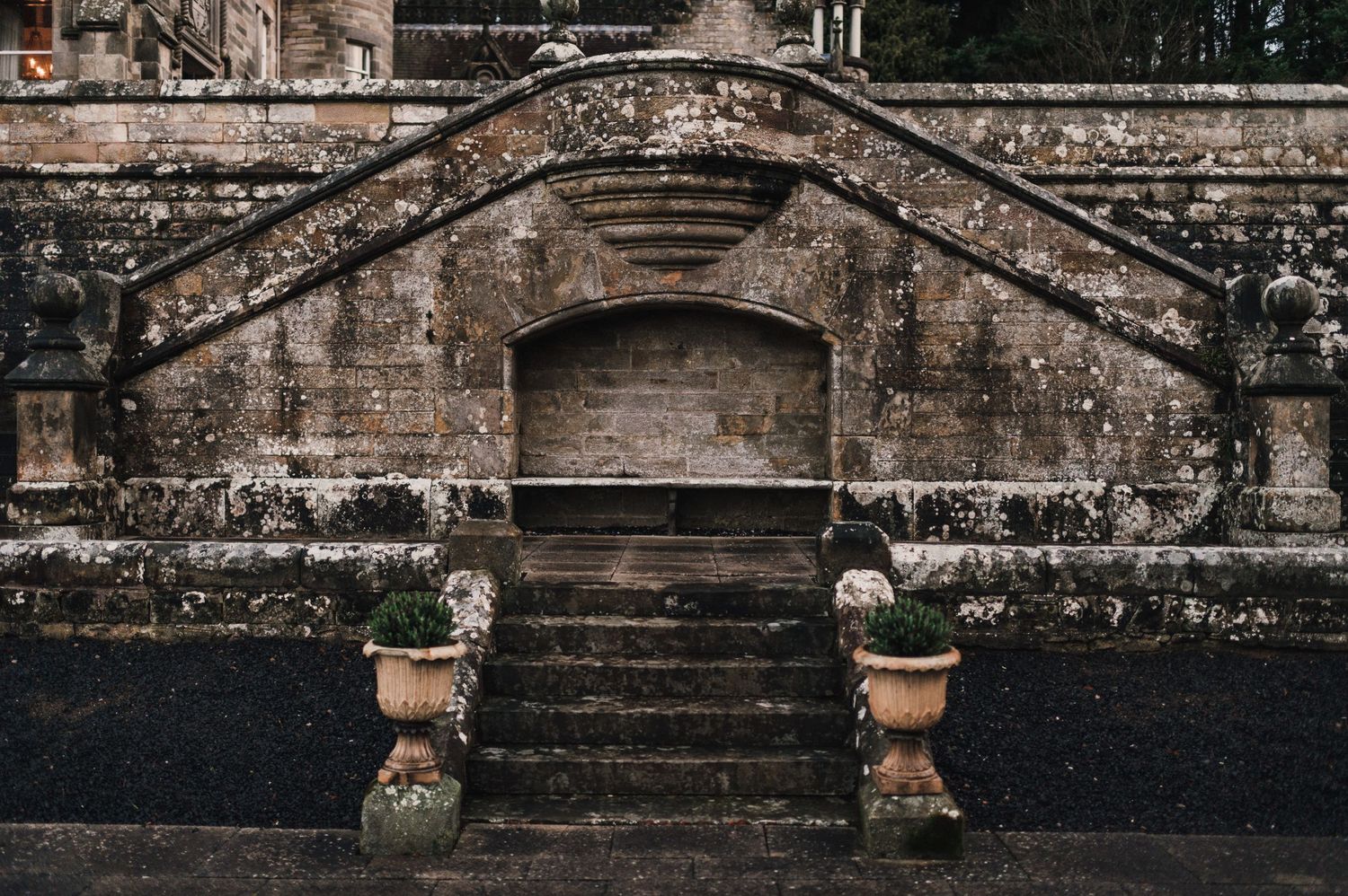Historic stone steps leading to an arched entrance with weathered urns on either side.