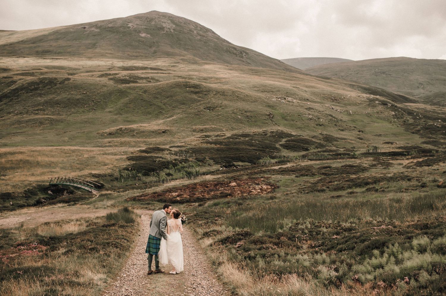 Couple walking hand in hand on a remote Scottish hillside path.