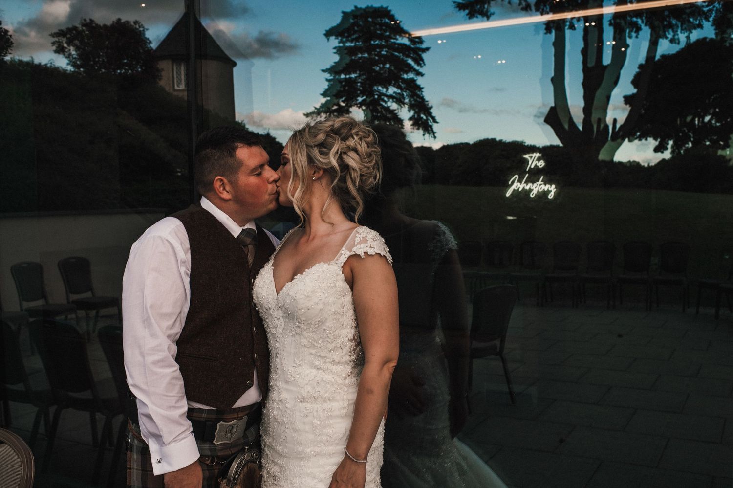 Evening wedding portrait with couple in front of historic building at dusk.