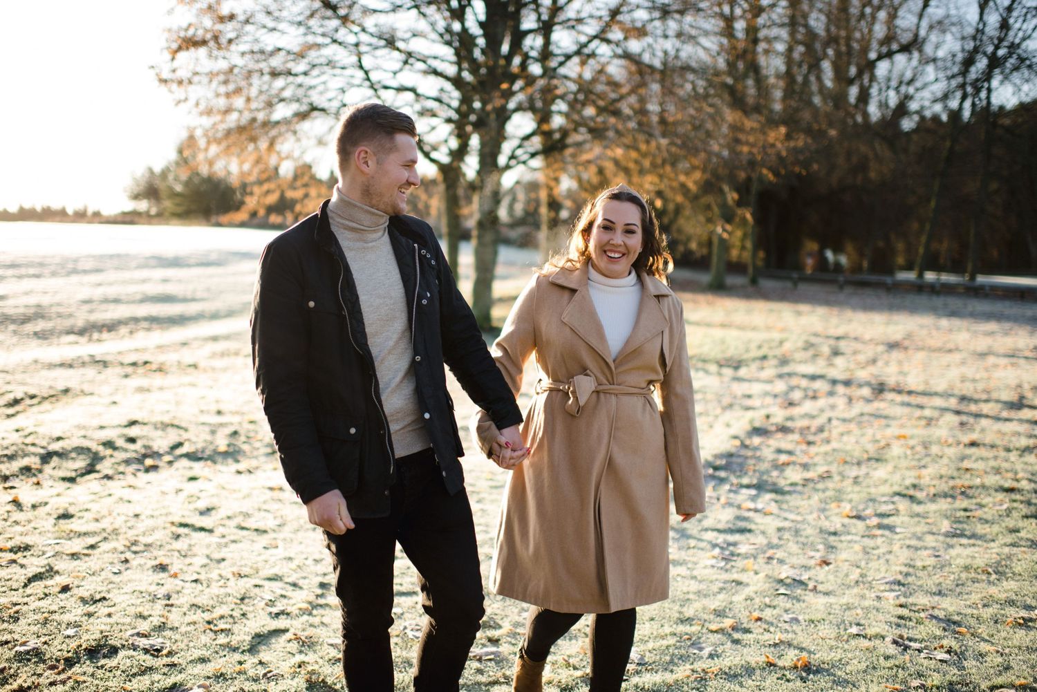 Couple taking romantic winter walk through park with fallen leaves.