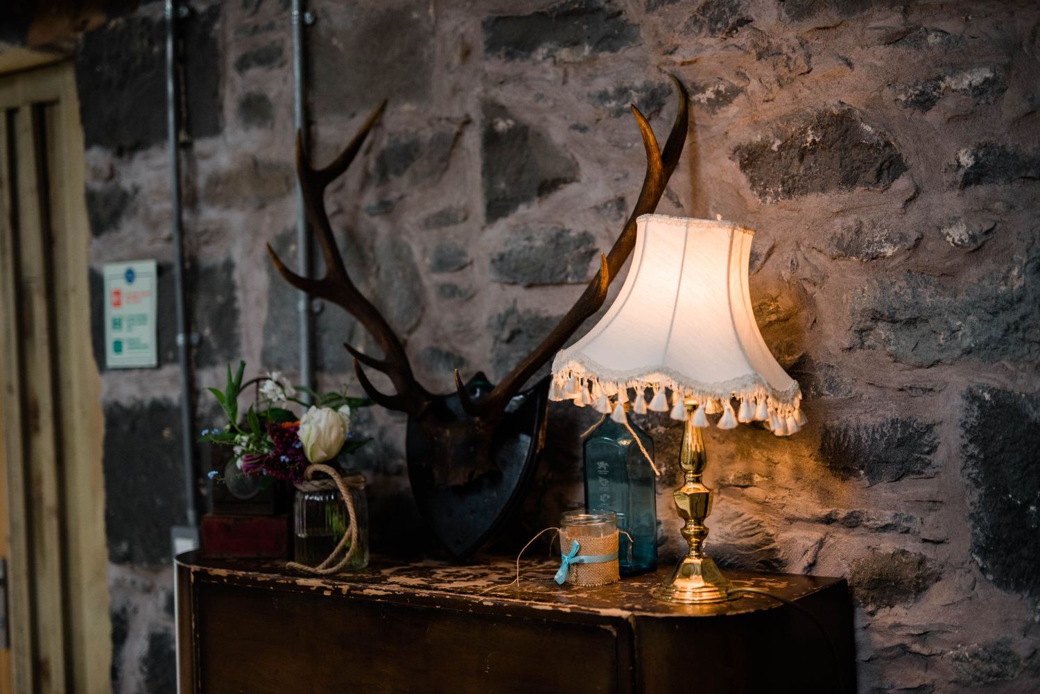 Vintage table lamp with fabric shade against stone wall creating warm ambient lighting.