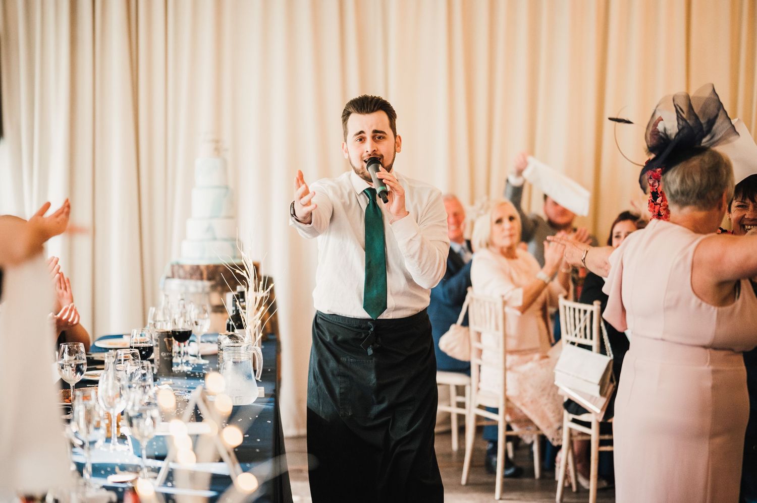 Logie House Wedding Photography. Wedding reception speaker addressing guests in formal attire at decorated venue.