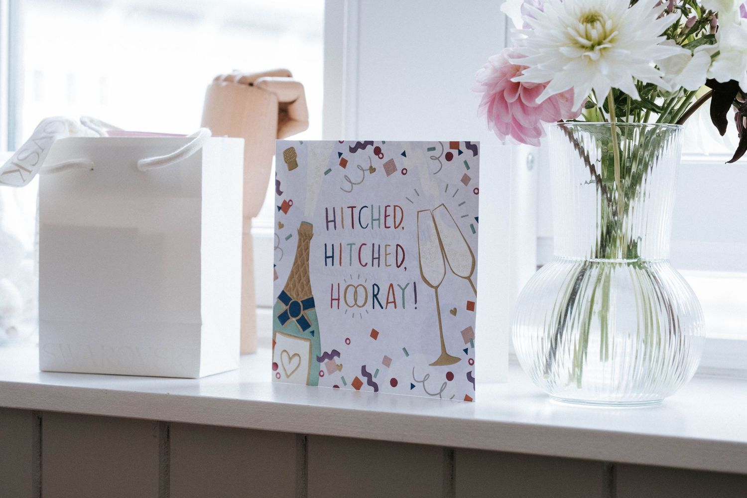 White floral arrangements and greeting cards displayed on a bright windowsill.