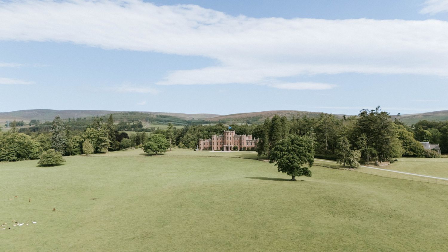 Aerial panorama of a historic castle estate surrounded by lush green countryside.